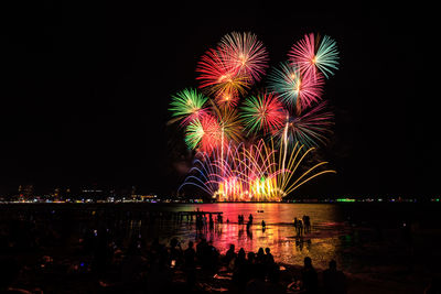 Low angle view of firework display over river at night