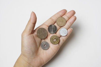 Close-up of hand holding coins over white background