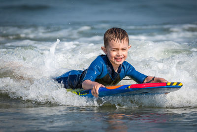 Portrait of boy swimming in sea on kneeboard