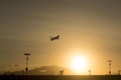 Low angle view of silhouette airplane against sky during sunset