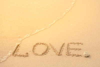High angle view of love text in sand on shore