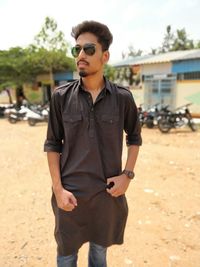 Young man wearing sunglasses standing on field