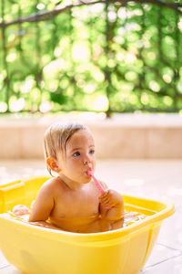 Portrait of shirtless boy sitting in bathroom