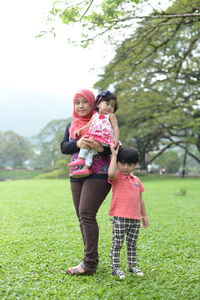 Mother with daughter and son standing on grass