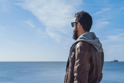 Rear view of man standing by sea against sky