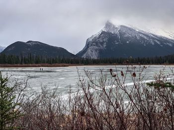 Scenic view of lake by snowcapped mountains against sky