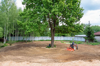 A man on a mini-excavator levels a piece of land, loosens the soil.