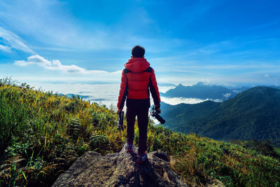 Rear view of man standing on mountain against sky