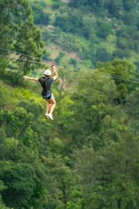 Young woman going on a zipline in the jungle. tree climbing in sri lanka. adventure concept