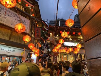 People in illuminated city against sky