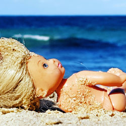 Close-up of doll lying on beach