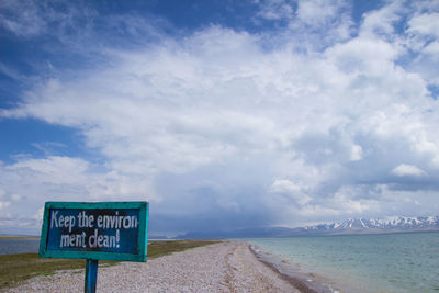 Information sign on beach against sky