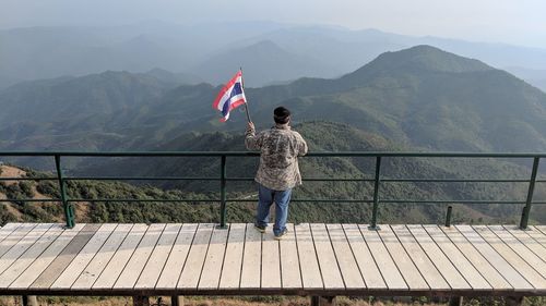 Rear view of man looking at mountain range against sky