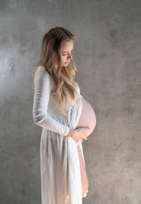 Beautiful young woman standing against wall