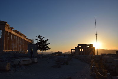 Parthenon on field against clear sky during sunset