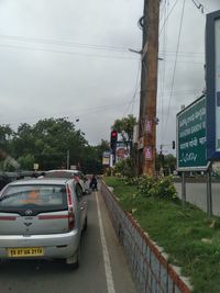 Vehicles on road against sky in city