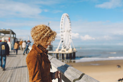 Side view of woman standing on scheveningen pier at beach during sunny day