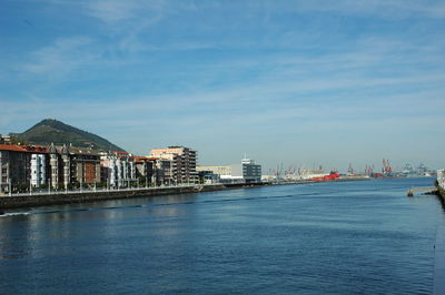 View of buildings by sea against cloudy sky
