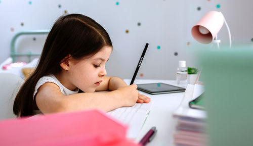Girl using mobile phone while sitting on table