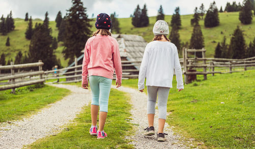 Rear view of women walking on grassland