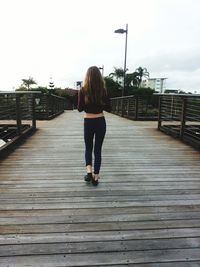 Rear view of woman walking on footbridge