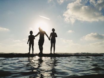 People on beach against sky during sunset