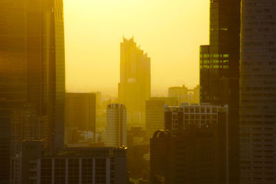 Modern buildings in city against sky during sunset