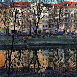 Bare trees against buildings reflection in canal