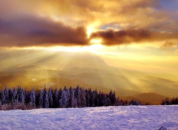 Scenic view of snow covered land against sky at sunset