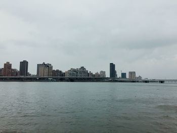 Sea by buildings against sky in city