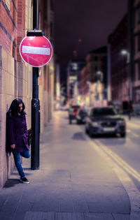 Woman leaning on wall in city at night