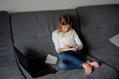 Portrait of young woman sitting on sofa at home