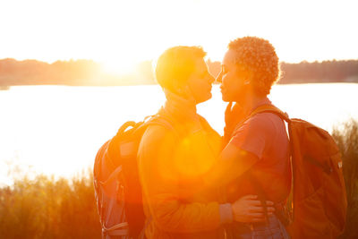 Rear view of man with arms raised against sky during sunset