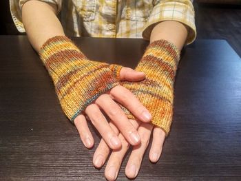 Close-up of woman wearing woolen gloves on table