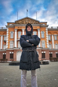 Portrait of man standing against building in city