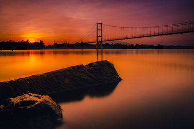 Bridge over river against sky during sunset