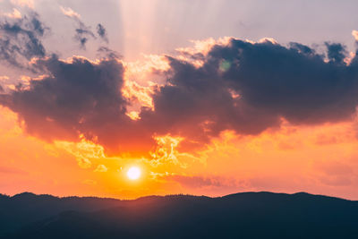 Scenic view of silhouette mountains against romantic sky at sunset