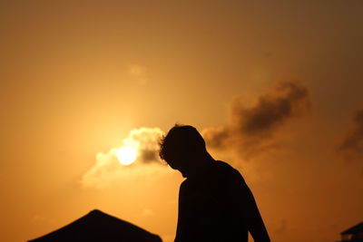 Silhouette of man against orange sky