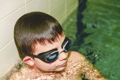 Boy in the indoor public pool. portrait of child with swimmng goggles.