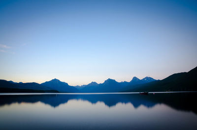 Scenic view of lake and mountains against clear blue sky