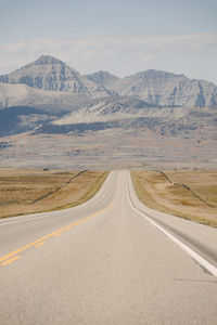 Road leading towards mountains against sky