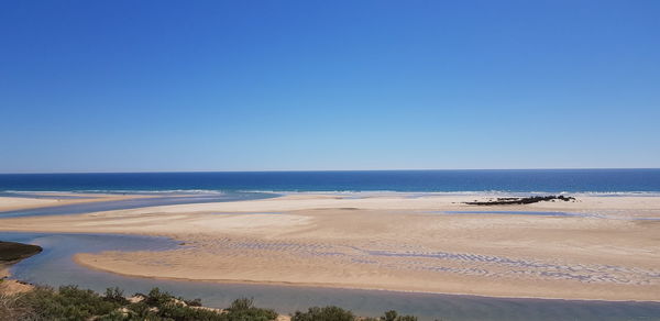 Scenic view of beach against clear blue sky