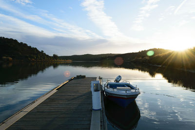 Boats moored in lake against sky during sunset