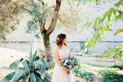 Young woman standing by plants