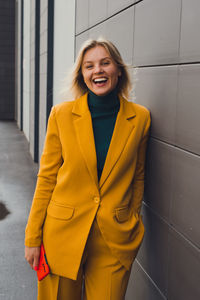 Portrait of young woman standing against wall