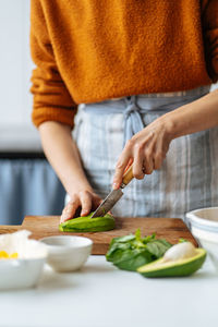 Woman cutting avocado on cutting board