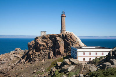 Lighthouse by sea against sky