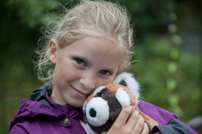 Close-up portrait of cute girl holding toy outdoors