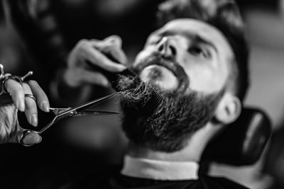 Close-up of woman cutting man beard at shop