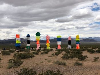 Rear view of people standing on field against cloudy sky